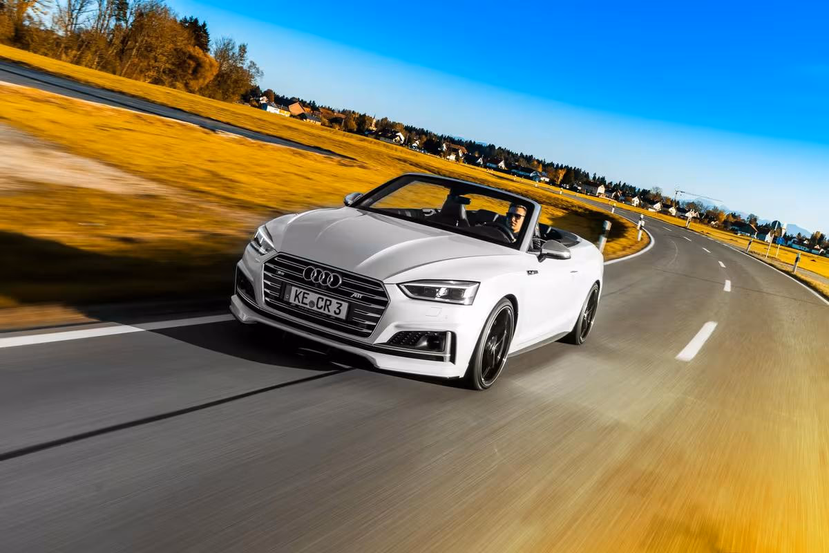 Weißer Audi Cabriolet fährt auf einer Landstraße durchs Allgäu.