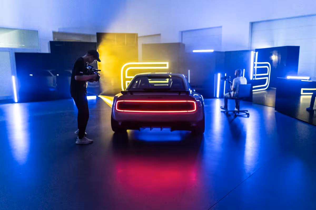 E-Legend: Rückansicht eines E-Autos mit rotem Leuchtring in blau-gelb beleuchtetem Studio.