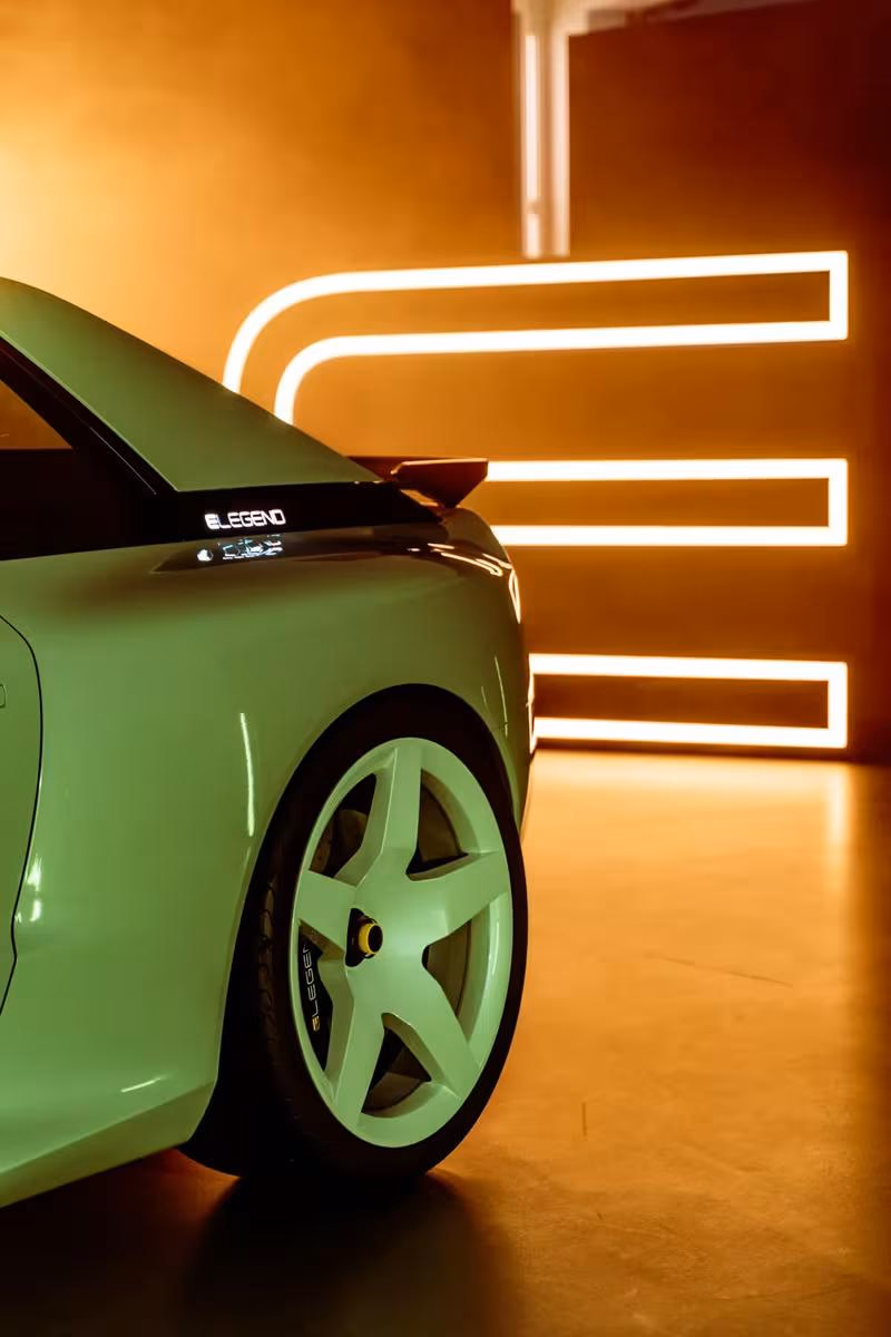 Grüner E-Legend-Rennwagen mit Leuchtbuchstaben im warmen Studio-Licht.