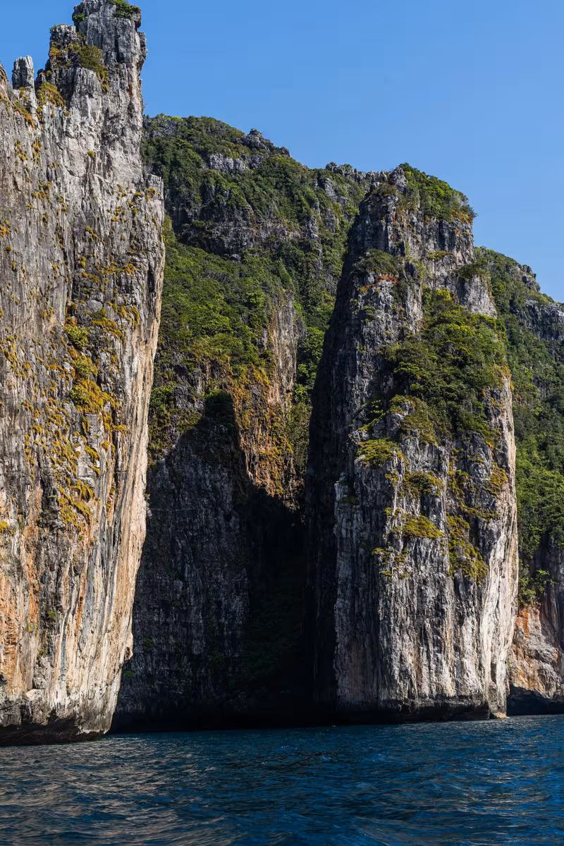 Thailand: Steile, bewachsene Felsklippen ragen direkt aus dem tiefblauen Meer.