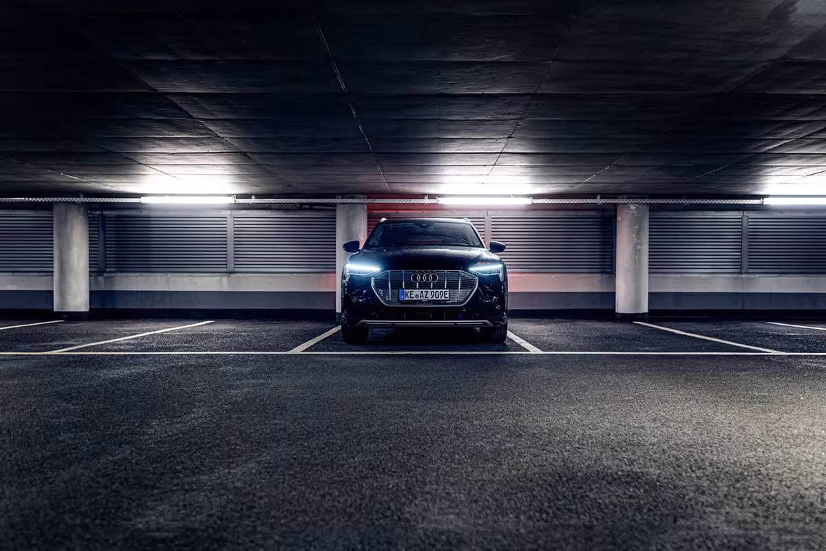 Black Audi e-tron with glowing headlights in a dark underground garage