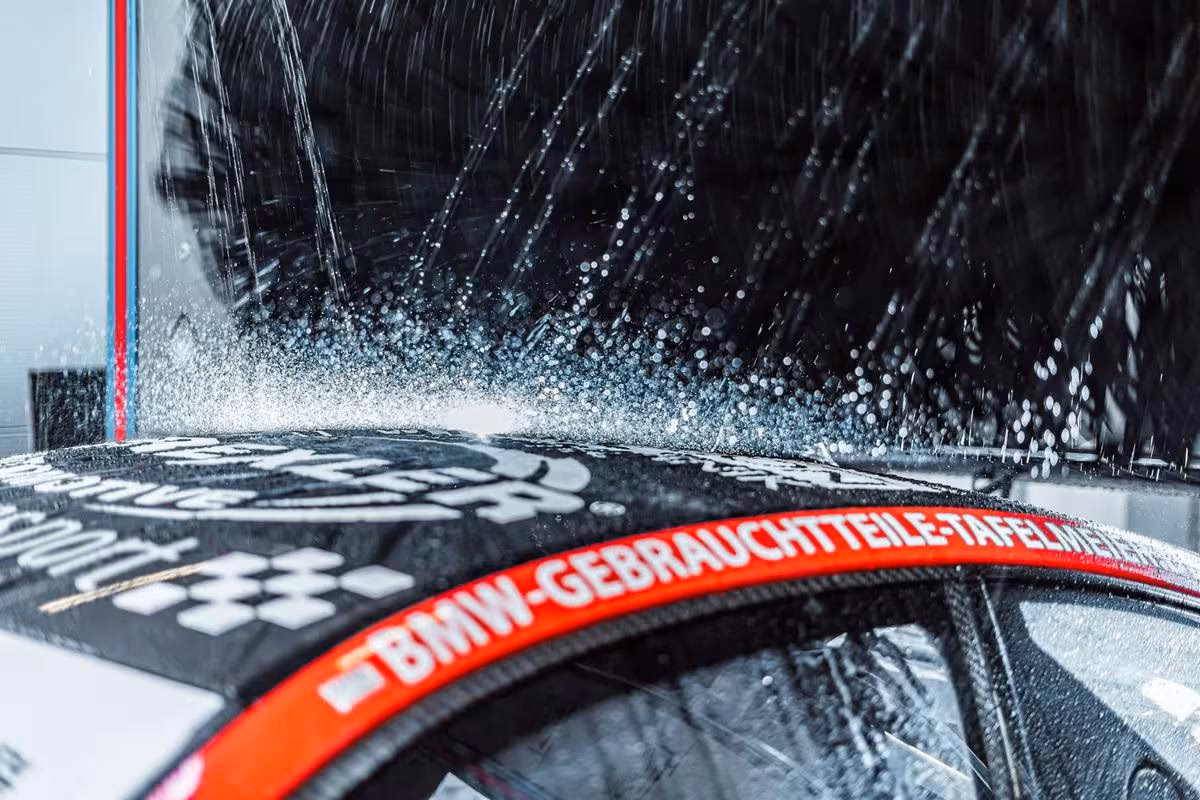 Christ Wash Systems: Wasserstrahl reinigt BMW-Fenster mit roter Schriftband-Beschriftung.