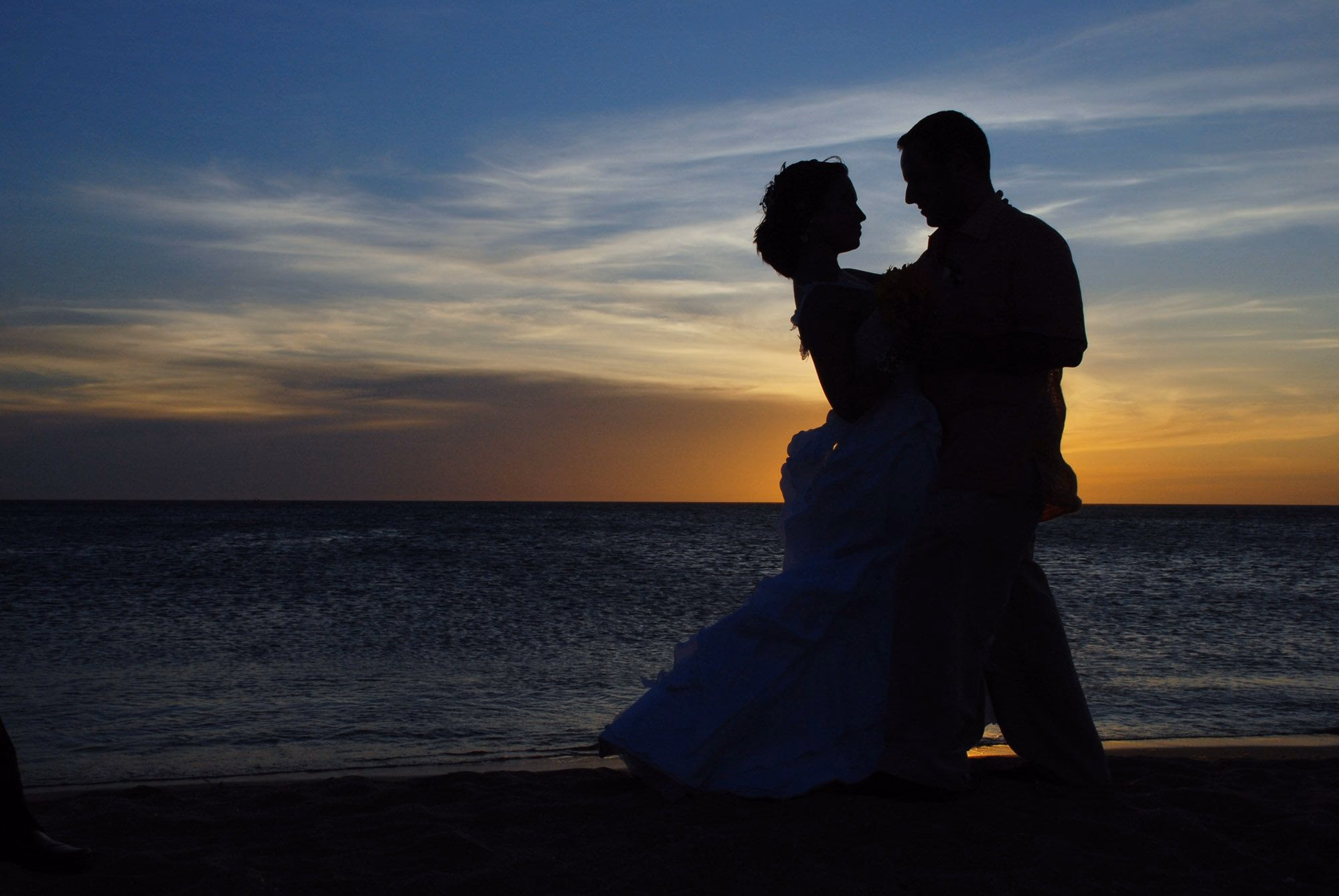 Silhouette eines Brautpaares am Meer bei Sonnenuntergang.