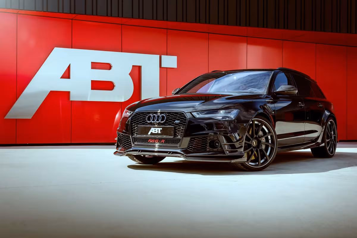 Audi: Schwarzer ABT RS6-R Avant vor roter Wand mit großem ABT-Logo.