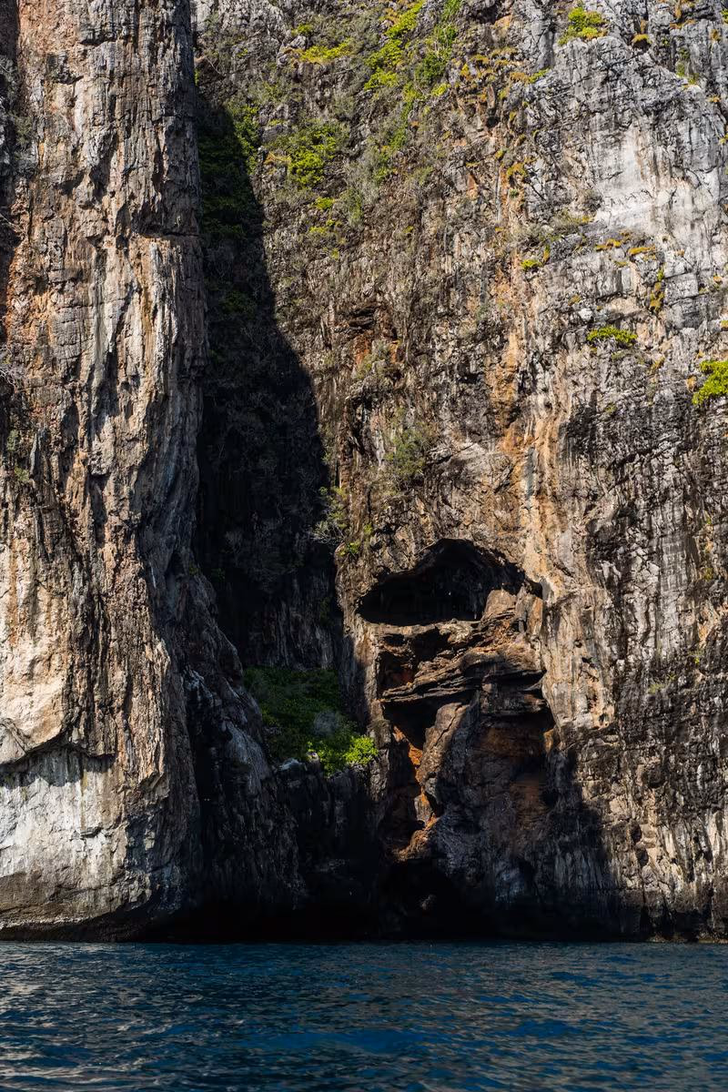 Thailand: Steile Felsklippe mit Höhle und Vegetation am Meer