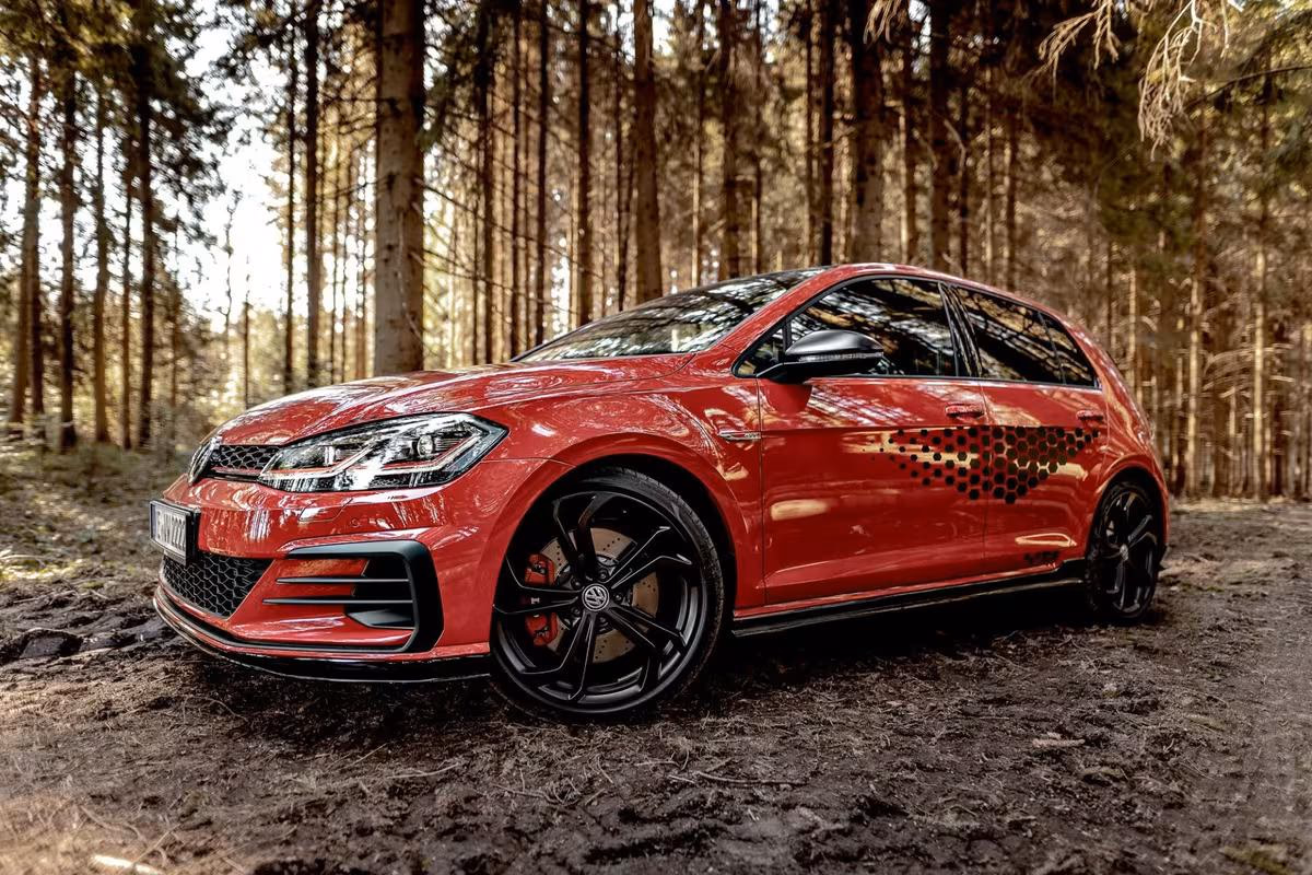 Volkswagen: Roter VW Golf GTI mit Punktmuster-Hecklackierung auf Waldweg