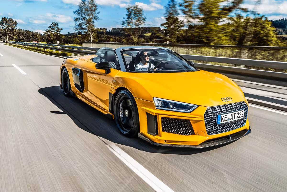 Gelber Audi R8 Spyder fährt mit hoher Geschwindigkeit auf einer Autobahn.