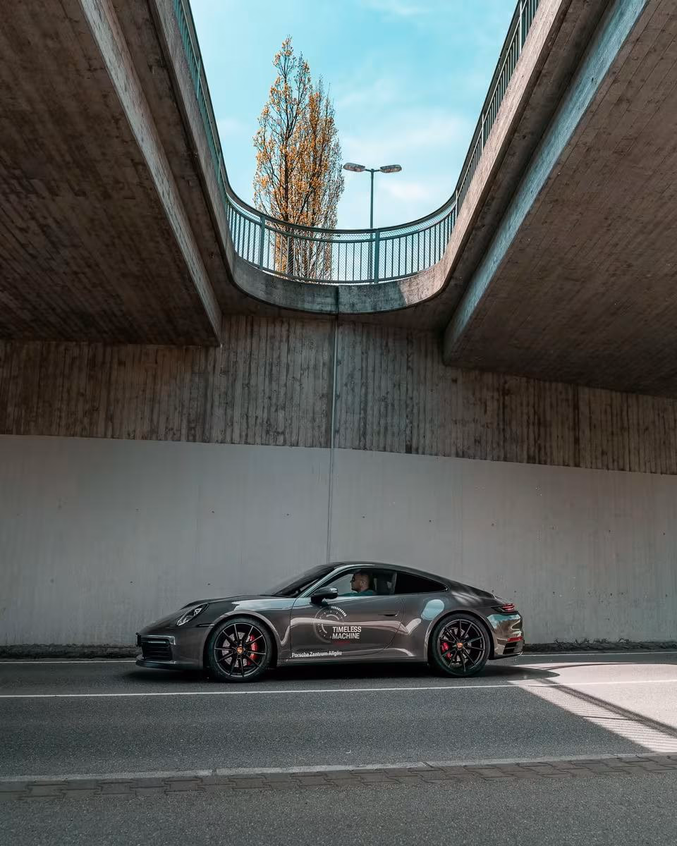 Seitz: Grauer Porsche 911 mit „Timeless Machine“-Aufdruck unter einer Betonbrücke.