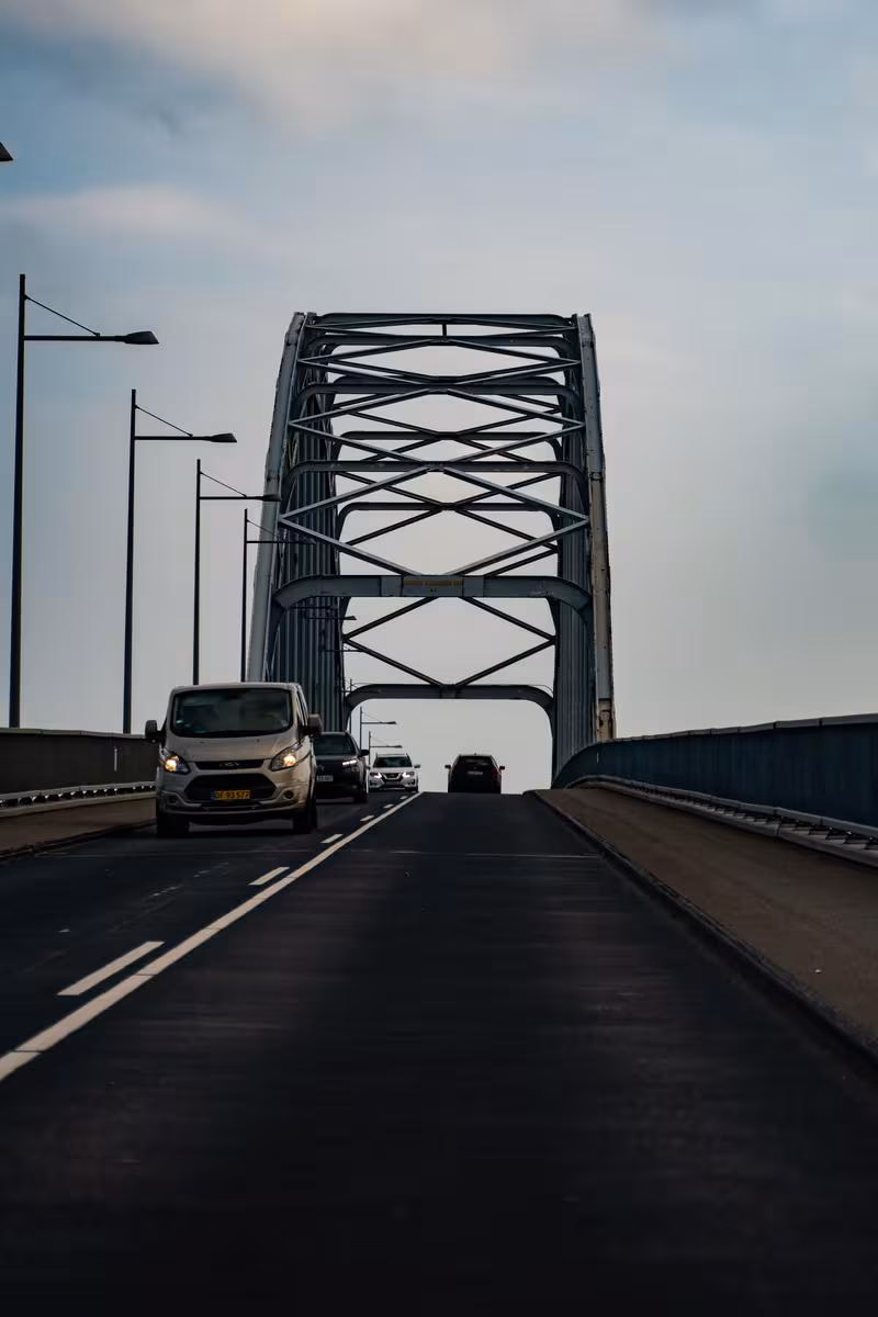 Copenhagen: Autos fahren auf einer Brücke mit großem Stahlbogen unter bewölktem Himmel.