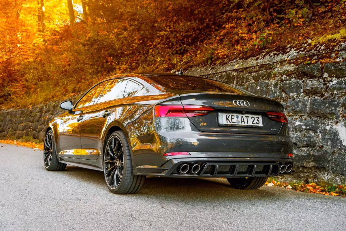 Schwarzer Audi RS7 Sportback von hinten auf einer Landstraße im Herbst.