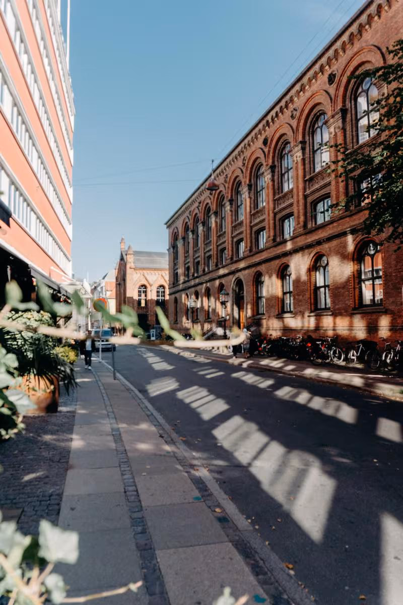 Copenhagen: Sonnige Straße mit historischem Backsteinbau und geparkten Fahrrädern in Kopenhagen.