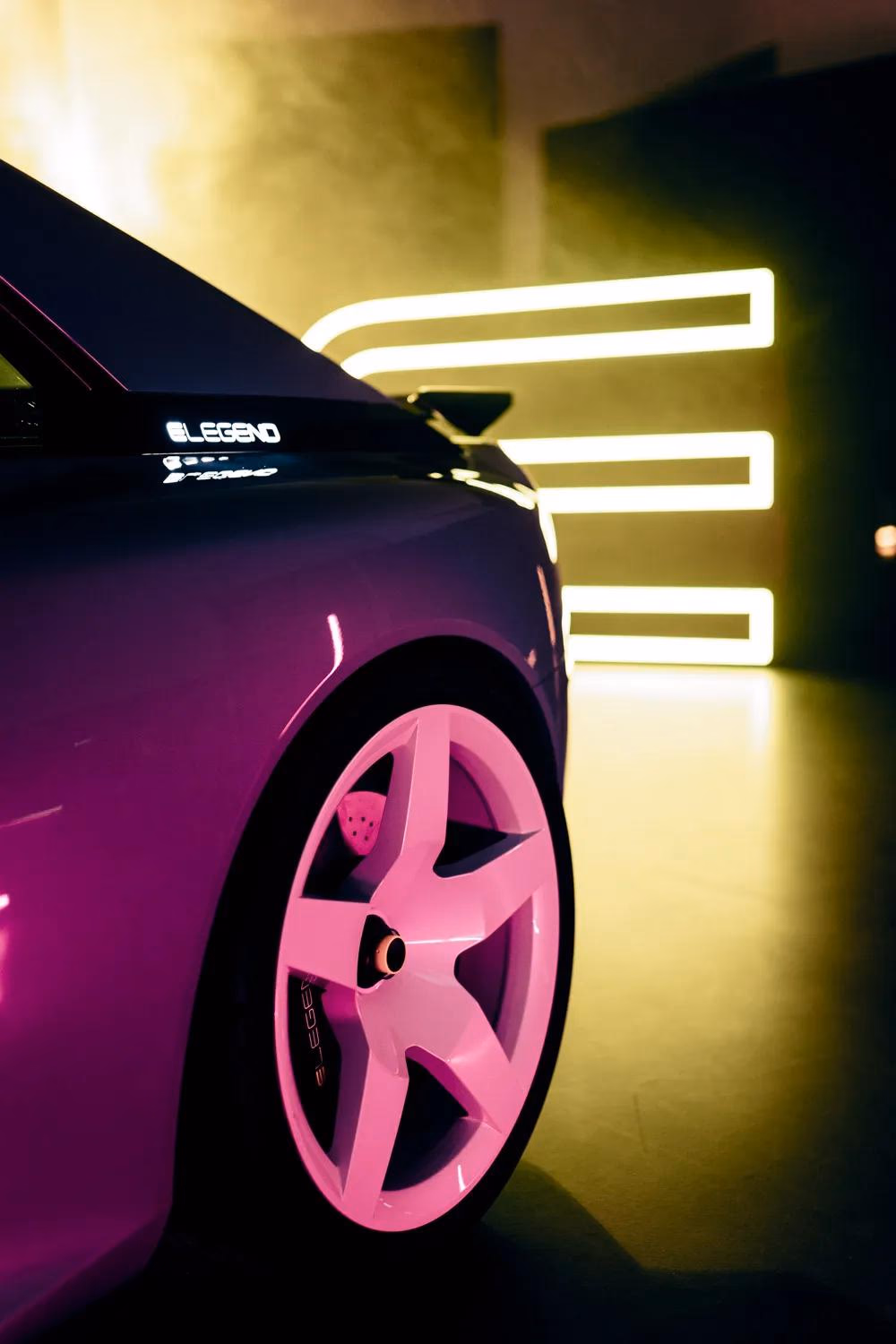 E-Legend Auto mit pinken Felgen vor gelben Neonlichtern