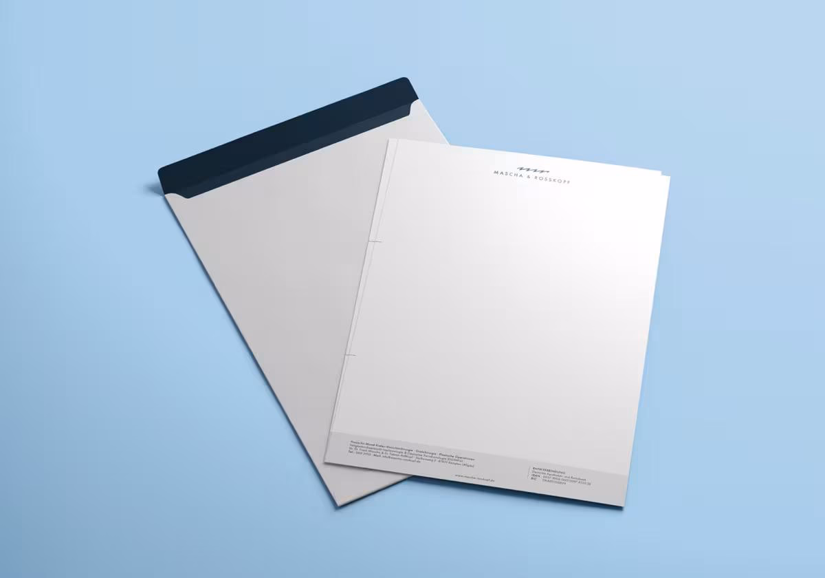 Briefpapier und Umschlag mit Logo „Mascha & Roßkopf“ auf hellblauem Hintergrund.