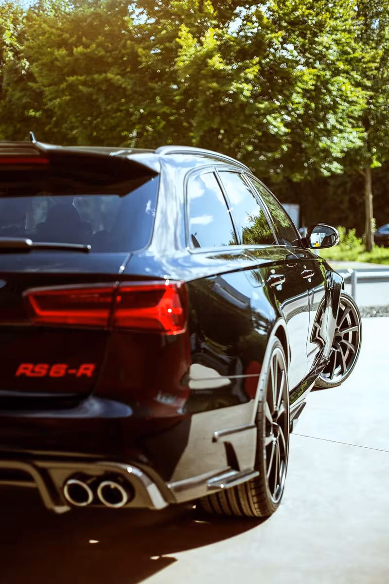 Schwarzer Audi RS 6 Avant mit roten Schriftzügen und Sportfelgen im Seitenprofil.
