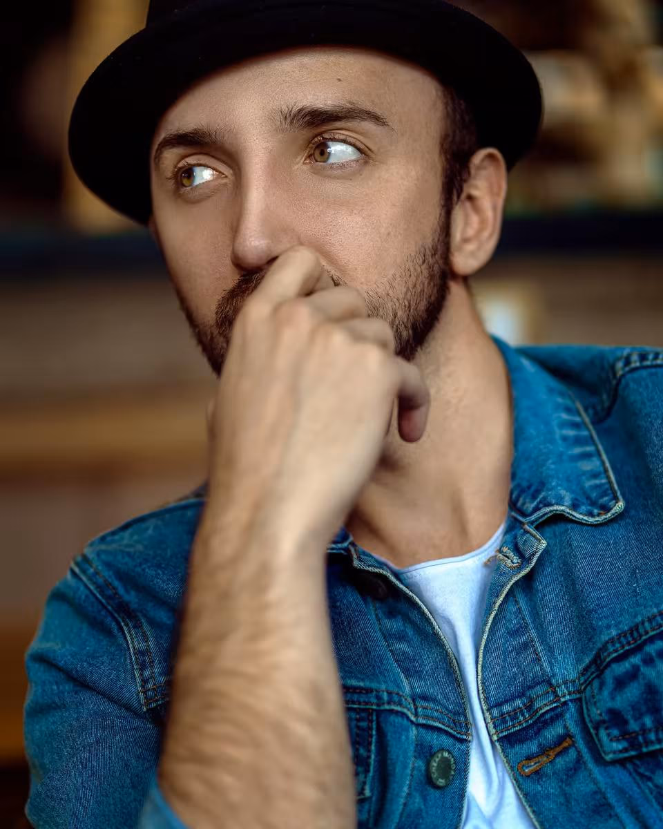 Lifestyle: Denkender Mann mit Hut und Jeansjacke in nachdenklicher Pose.