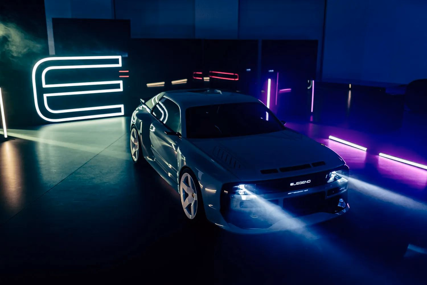 Silberner E-Legend-Sportwagen in dunkler Halle mit Neonbeleuchtung