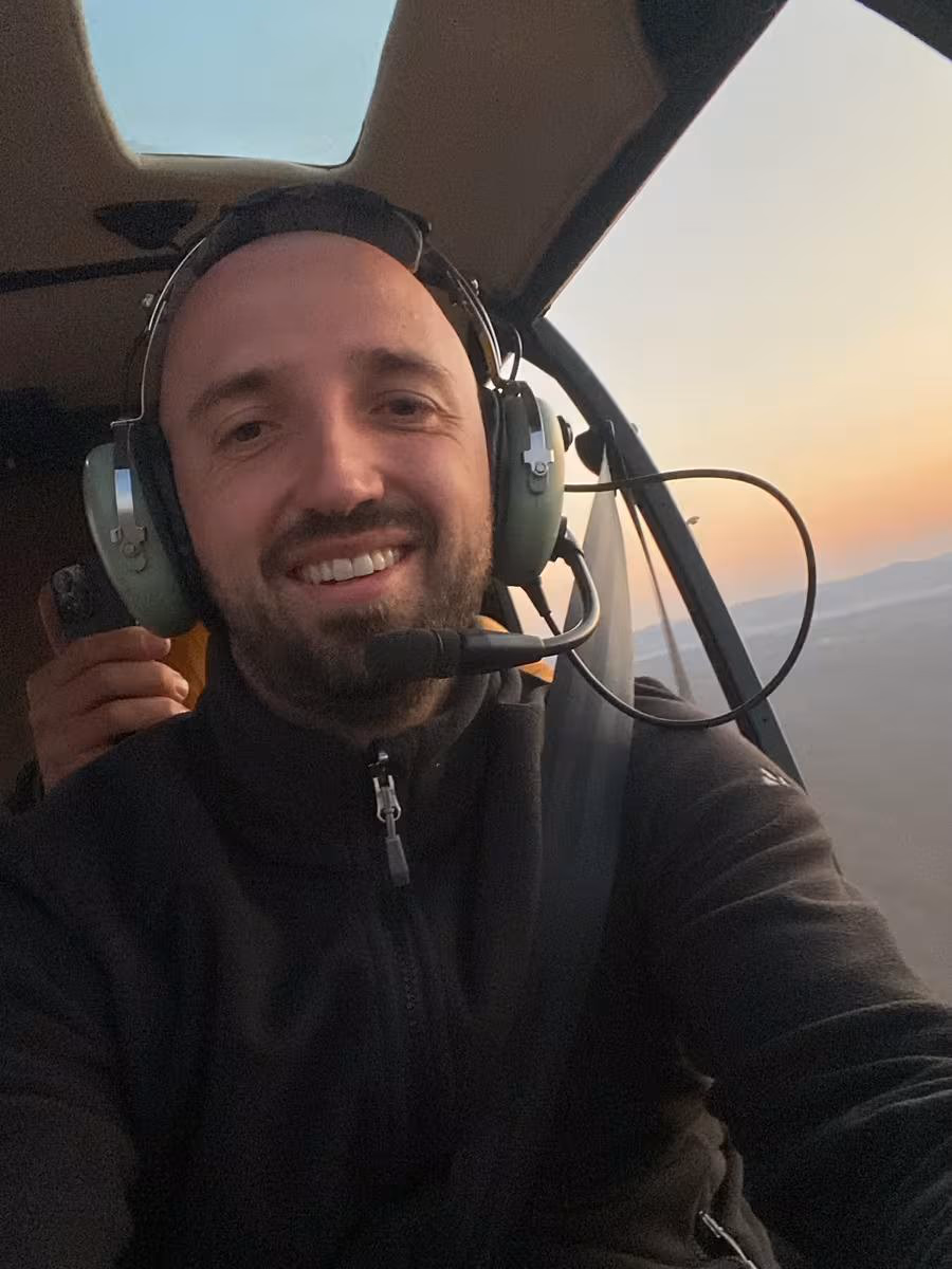 Fujifilm: Lächelnder Mann mit Headset im Hubschrauber bei Sonnenuntergang.