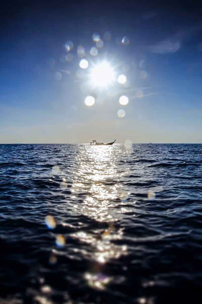 Lifestyle: Kleines Boot auf offener See bei strahlendem Sonnenschein und Linsenblitz.