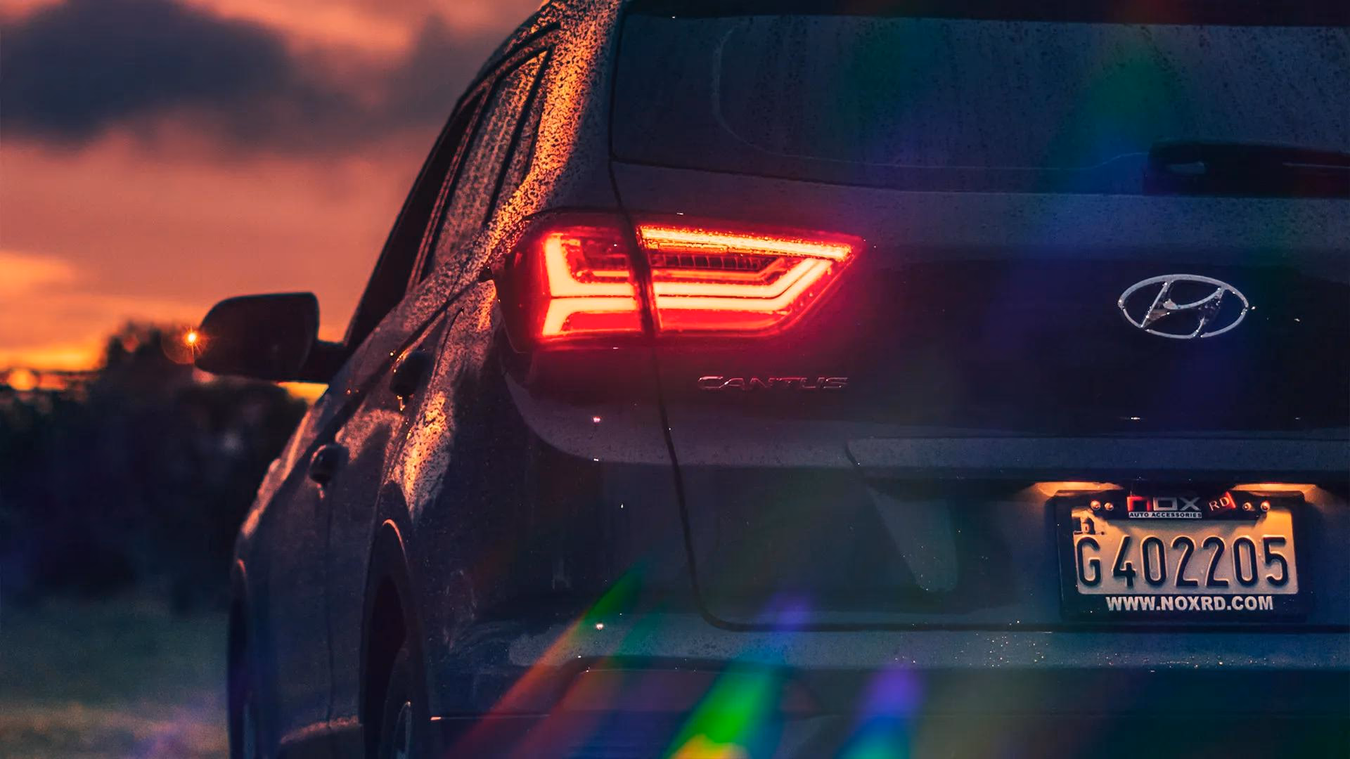 Hyundai i30 mit leuchtenden RGB-Lichtlecks am Heck bei Sonnenuntergang