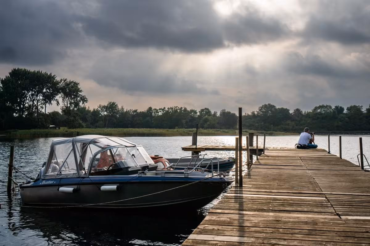 Copenhagen: Boot am Holzsteg auf einem See unter dramatischem, bewölktem Himmel.