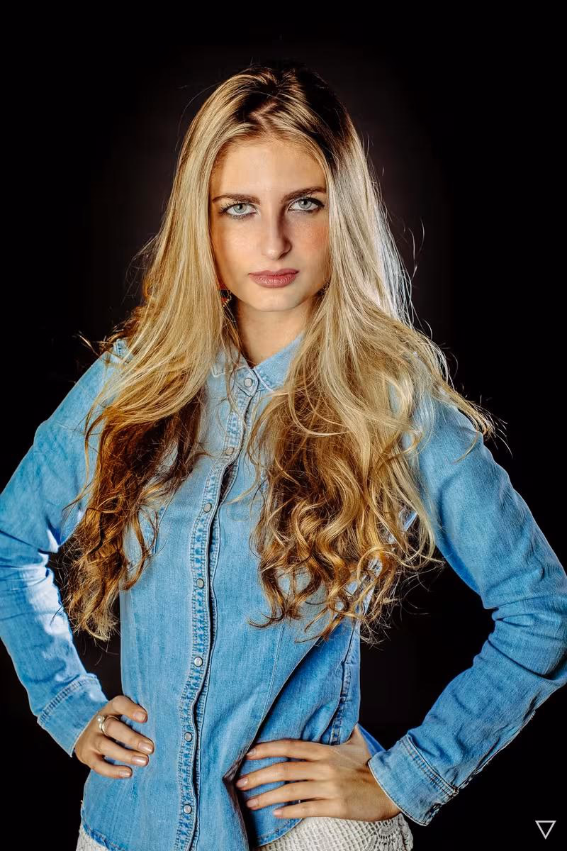 Lifestyle: Porträt einer blonden Frau in Jeanshemd vor schwarzem Hintergrund