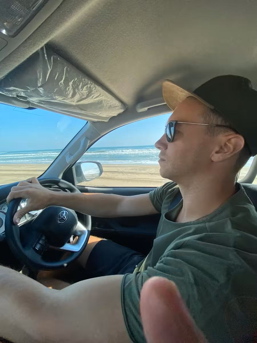 Fujifilm: Mann fährt in einem Toyota am Strand entlang.