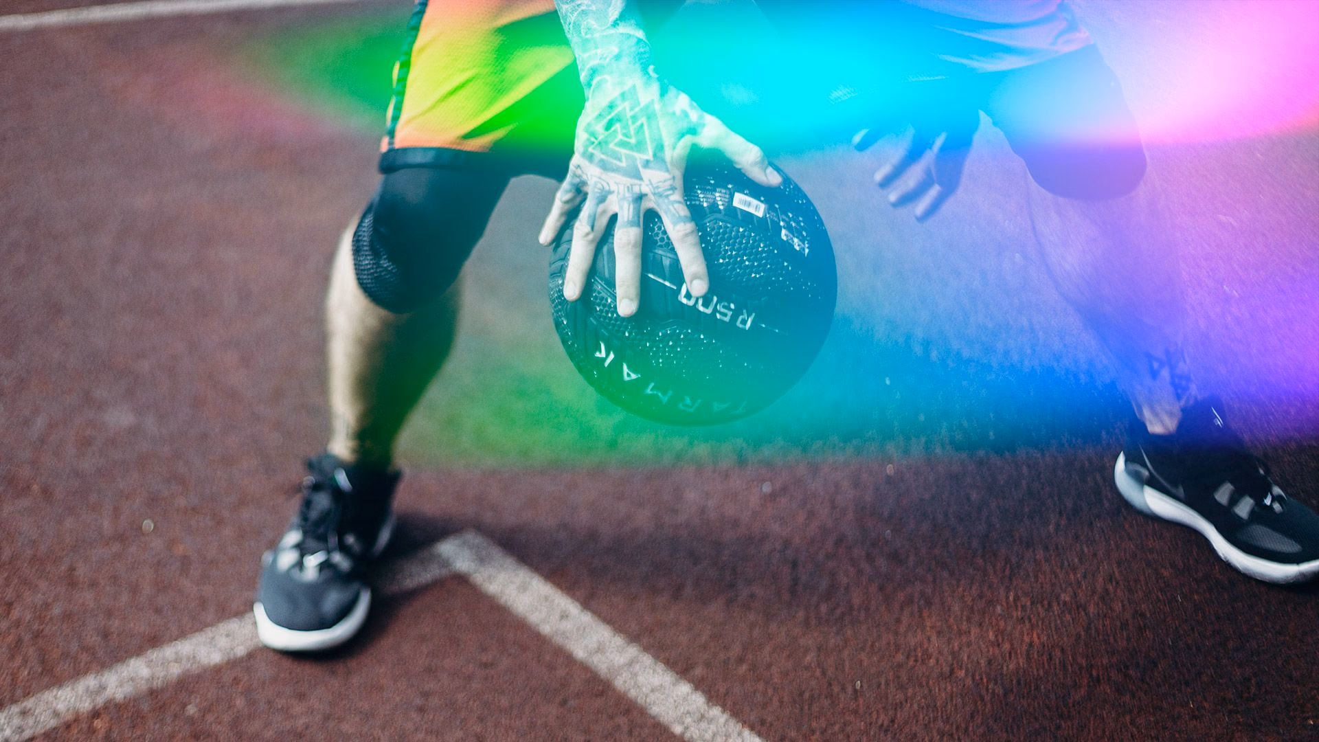 Athlet mit Medizintattoo fängt einen Medizinball auf der Laufbahn.