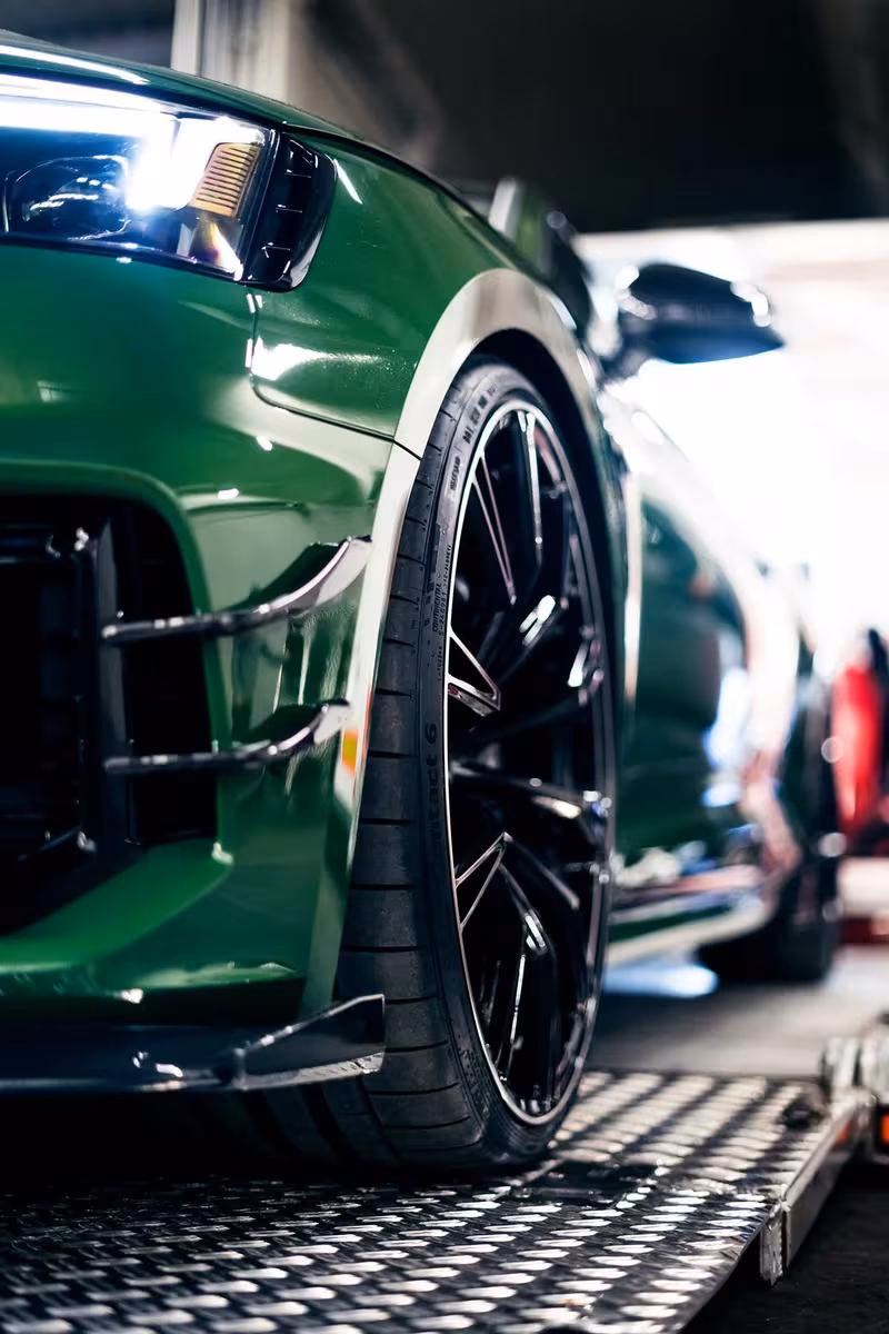 ABT: Nahaufnahme eines grünen ABT-Rennwagens mit schwarzem Sportfelge auf Rillenblech.