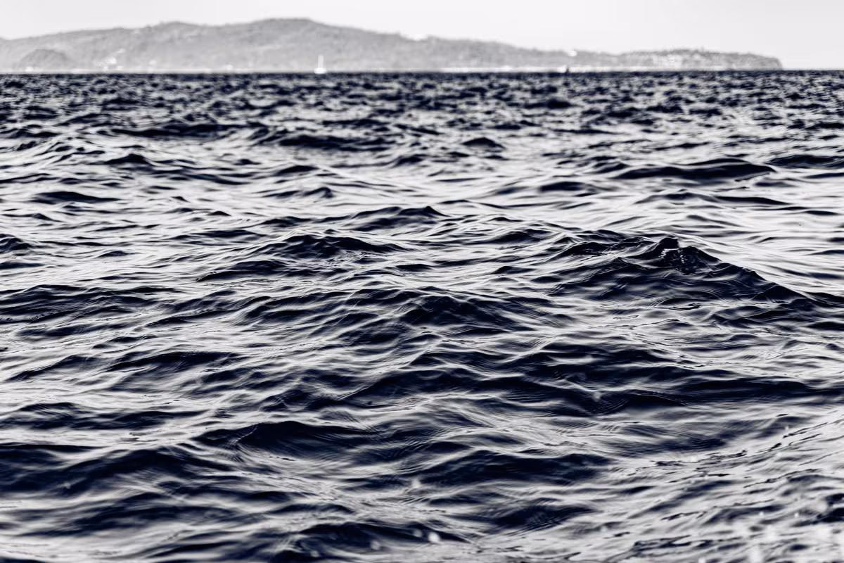 Thailand: Schwarzes Meer mit Wellen und ferner Küste im Hintergrund