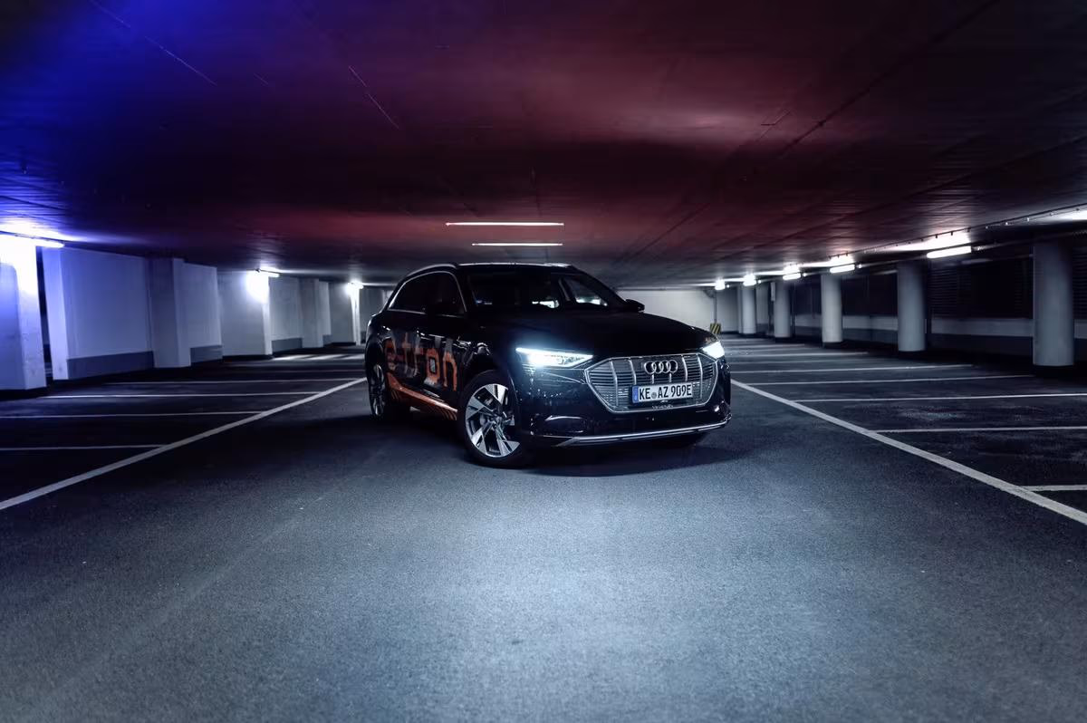 Black Audi e-tron with neon lighting in an empty underground parking garage