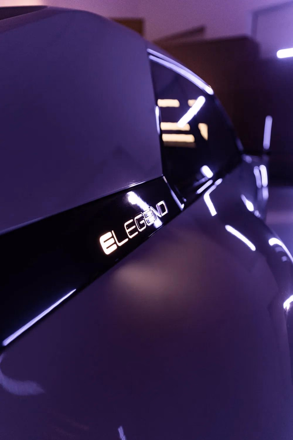 Schwarzer Lautsprecher mit leuchtendem „E-LEGEND“-Logo in violetter Beleuchtung