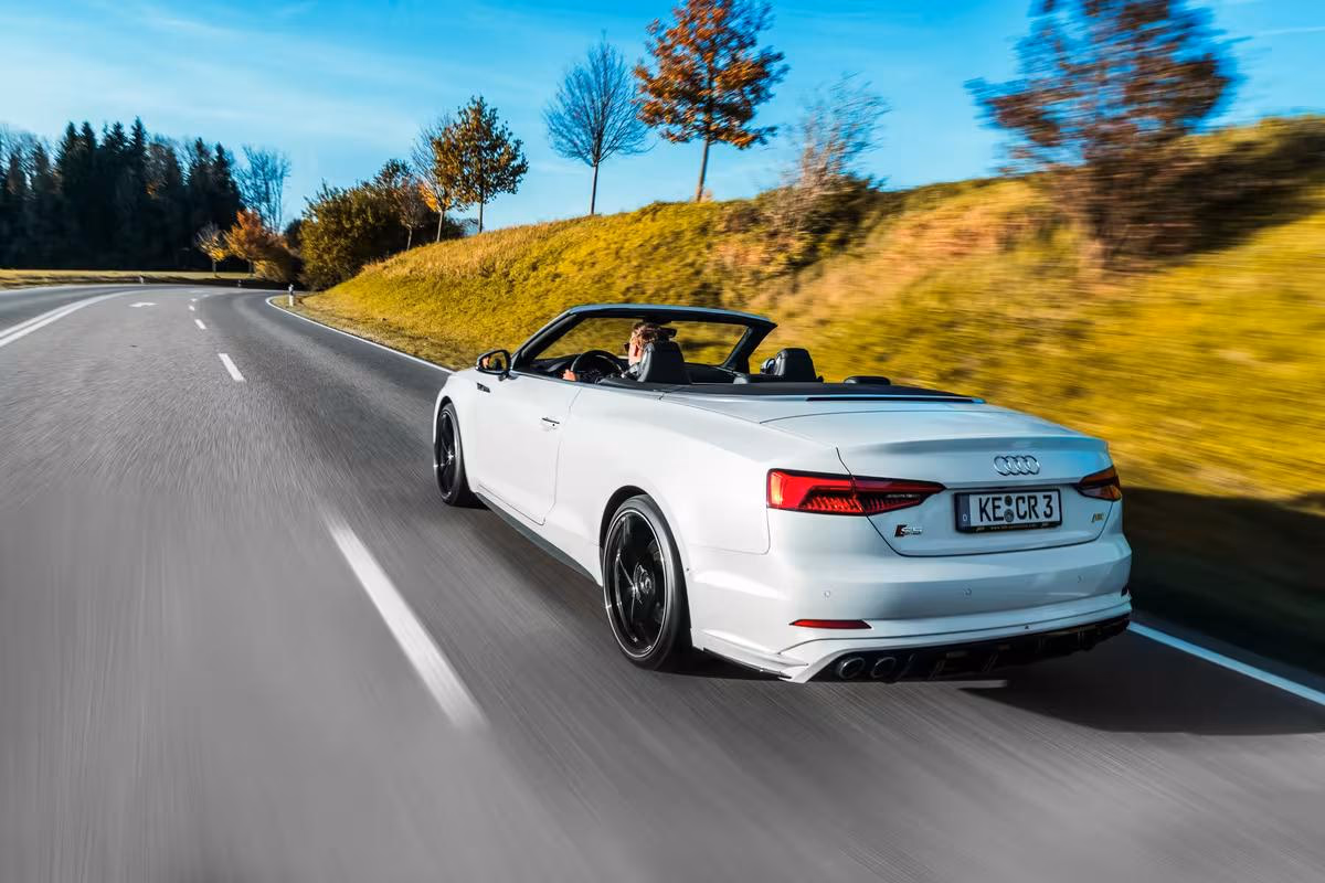 Weißer Audi Cabriolet fährt auf einer Landstraße durchs Allgäu.