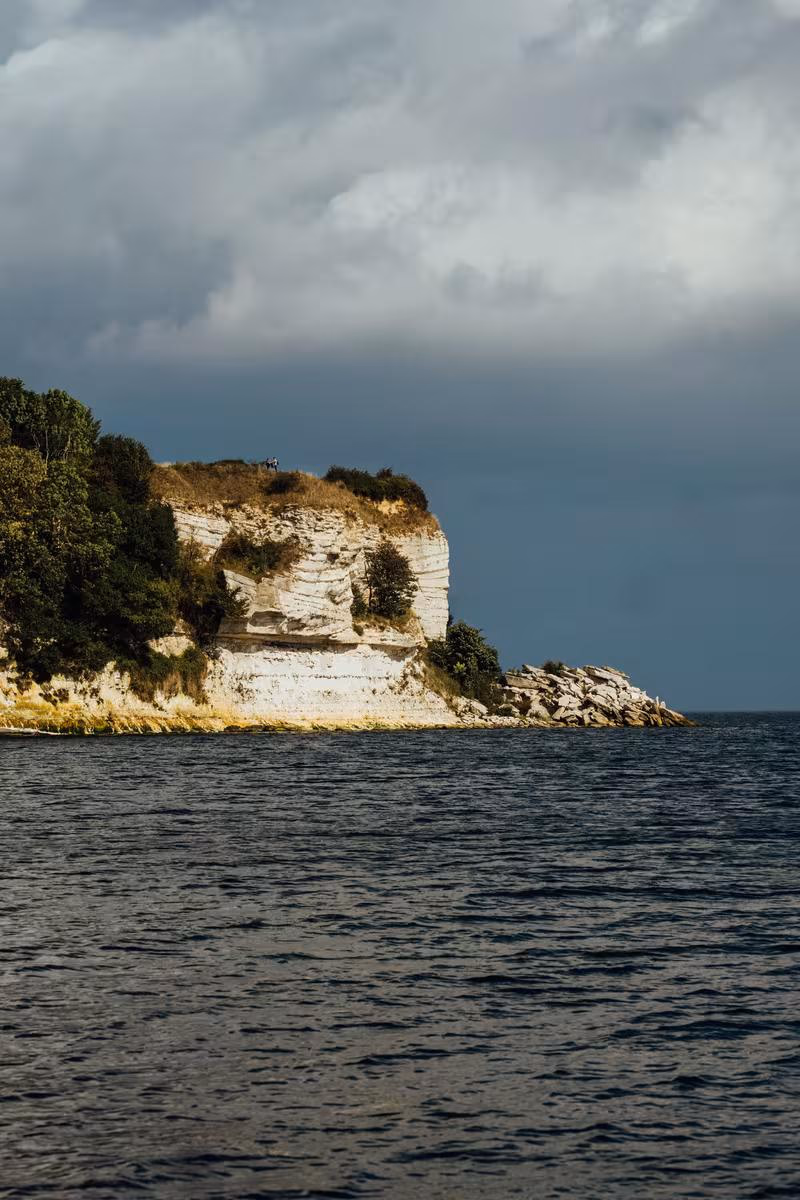 Copenhagen: Weiße Klippe mit Vegetation am Meer unter dramatischem, bewölktem Himmel