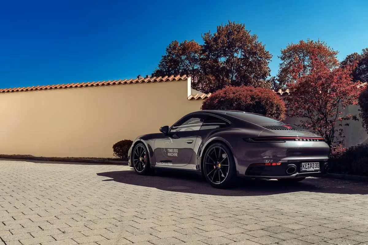 Dunkler Porsche 911 Carrera 4S mit Folierung vor einer Mauer