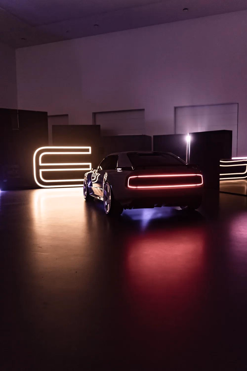 Schwarzer E-Legend-Sportwagen mit roter LED-Leiste vor leuchtendem Logo.