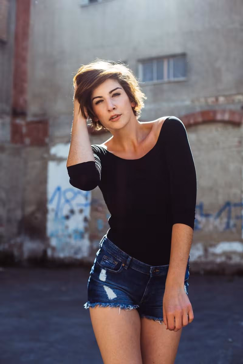 Lifestyle: Frau in schwarzem Top und Jeansshorts vor verwitterter Wand mit Graffiti