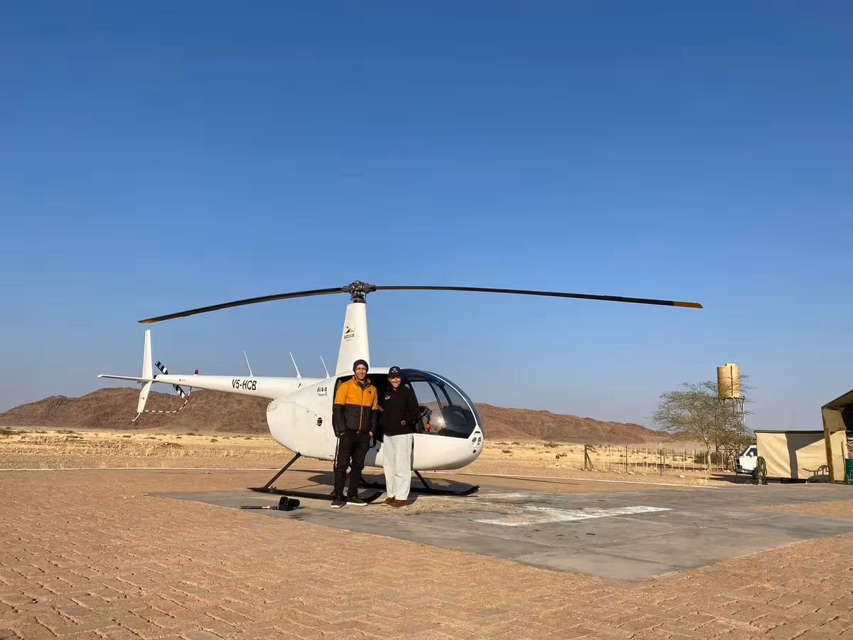 Fujifilm: Zwei Personen stehen vor einem weißen Hubschrauber auf einer Wüstenlandebahn.