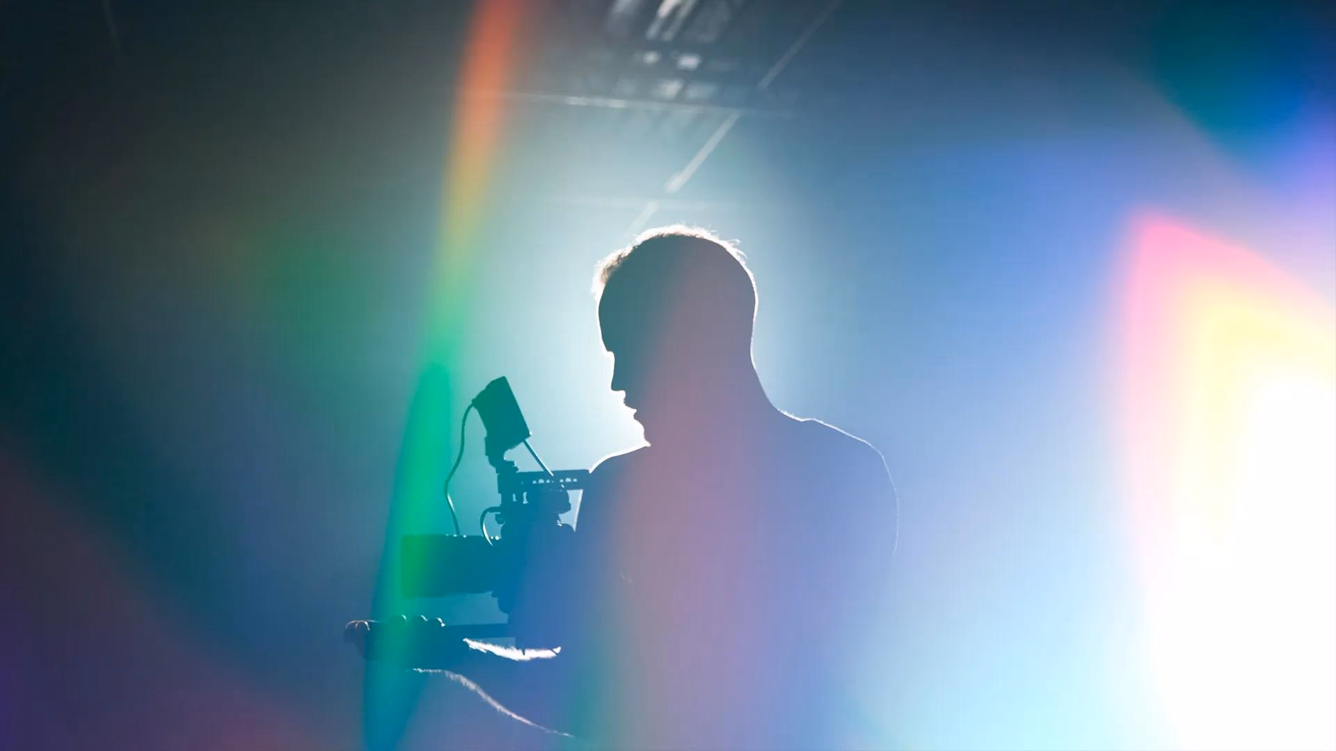 Silhouette eines Mannes mit Kamera vor bunten Lichtlecks