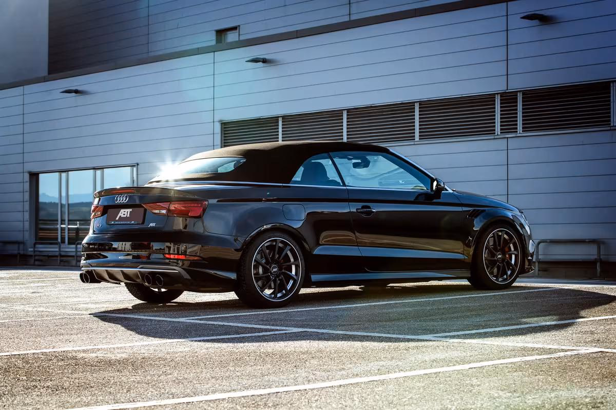 Schwarzer Audi Cabriolet mit ABT-Logo vor modernem Gebäude