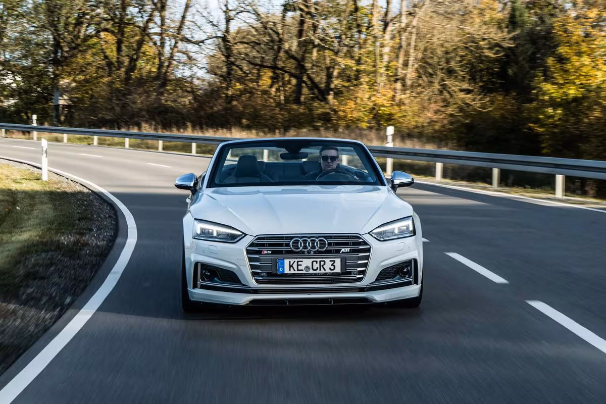 Weißer Audi S5 Cabriolet fährt auf einer Landstraße durch den Wald.