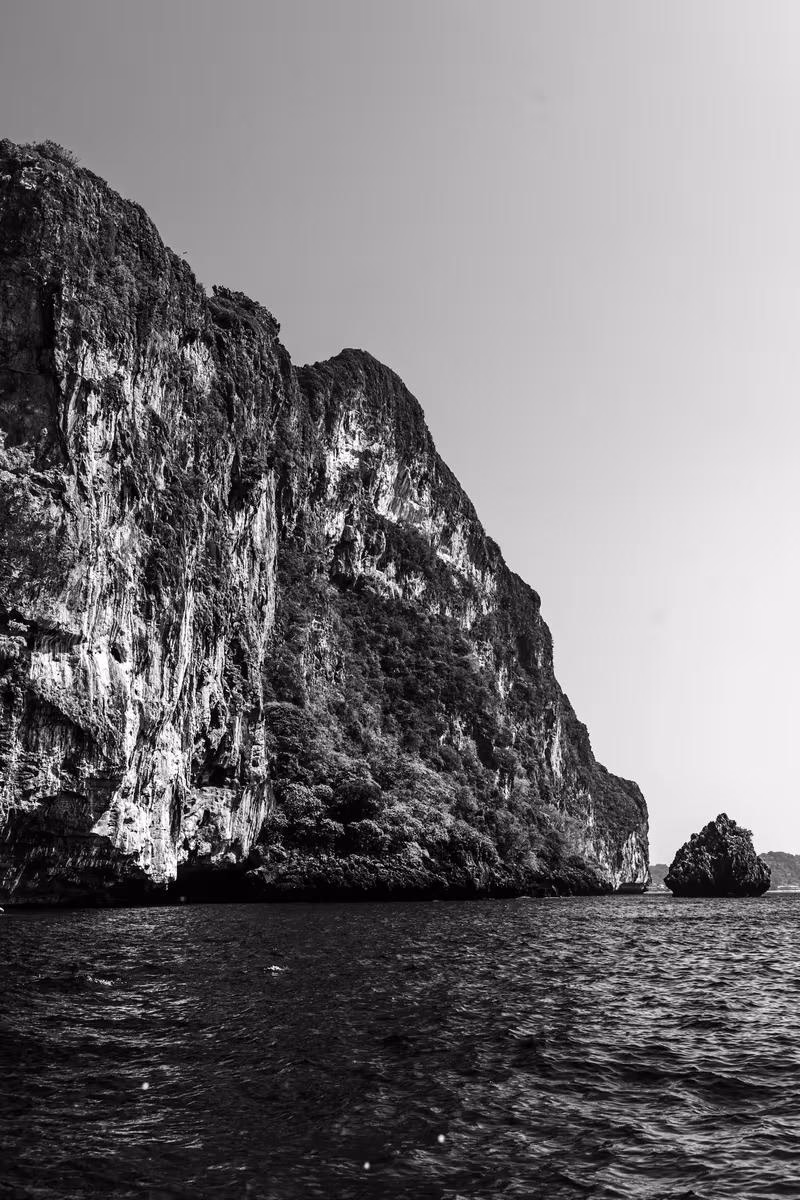 Thailand: Schwarzes-Weiß-Foto einer steilen Klippe und eines Felsens im Meer