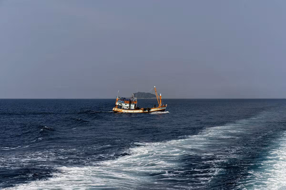 Thailand: Fischboot mit Kran auf offener See bei bewölktem Himmel