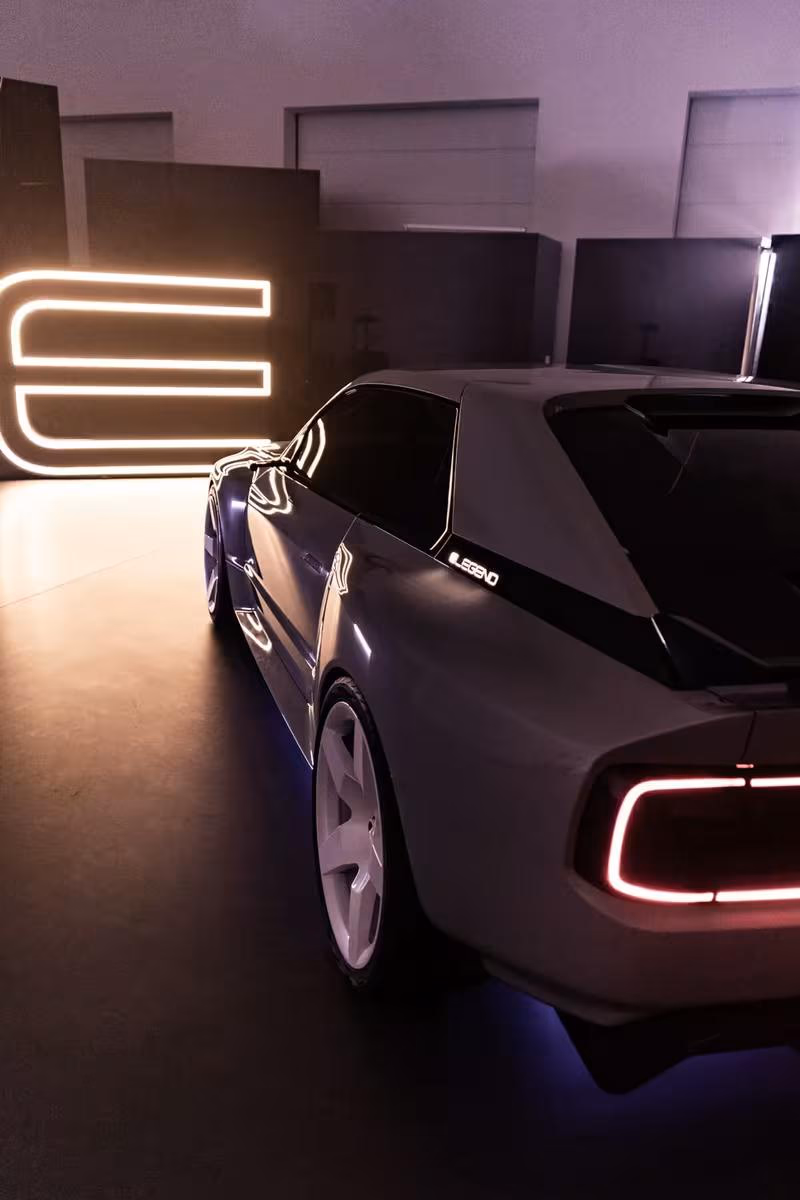 Silhouettansicht des E-Legend-Prototyps vor leuchtendem Neon-Logo in dunkler Halle.