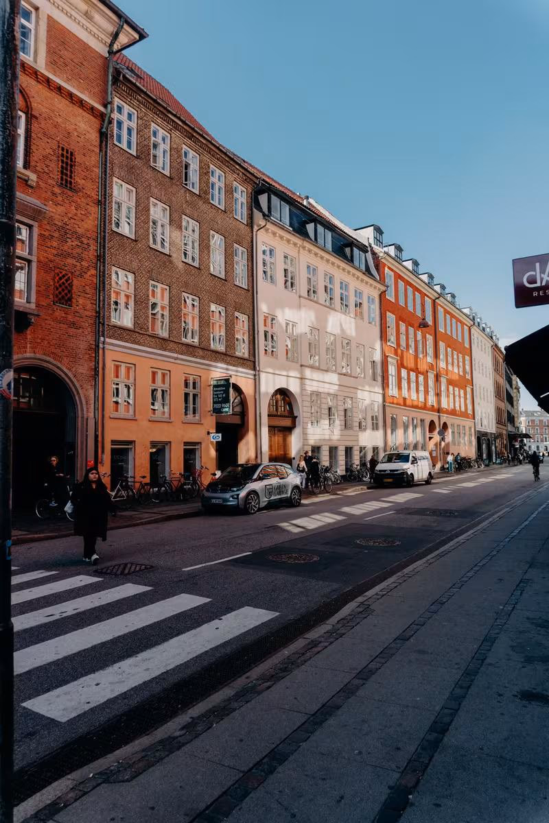 Copenhagen: Bunte Kopenhagener Straßenszene mit historischen Backsteinfassaden und parkenden Autos.