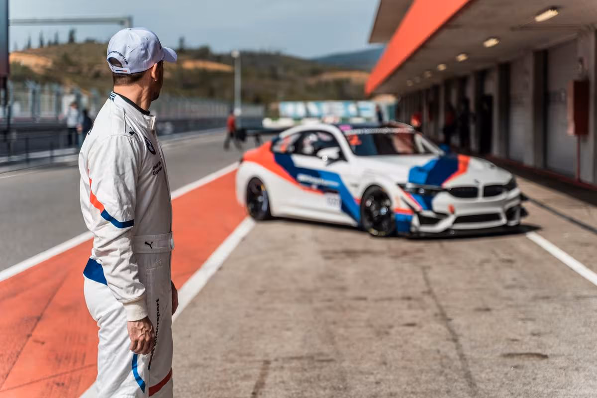 BMW Motorsport: Rennfahrer im BMW-Overall vor einem BMW M4 GT3 in der Boxengasse.