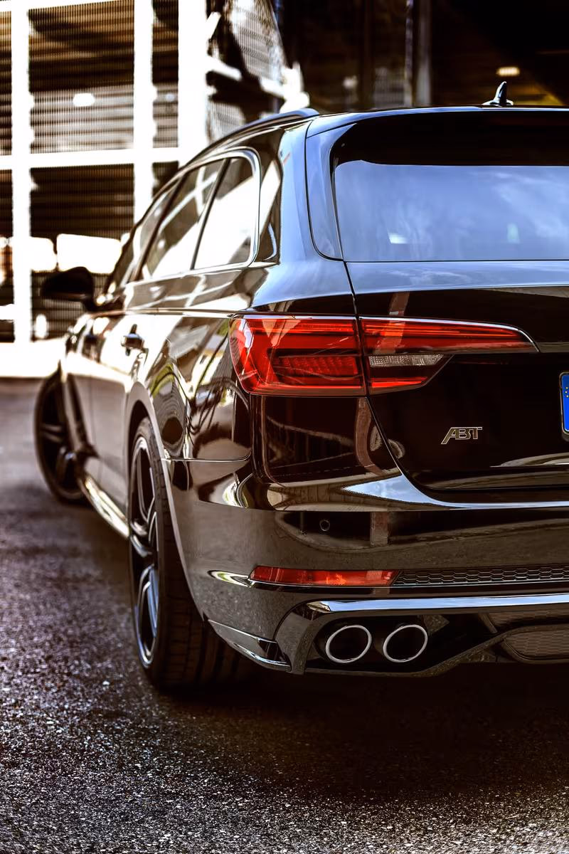 Audi: Schwarzer ABT Sportback mit Doppelauspuff, fotografiert von hinten seitlich.