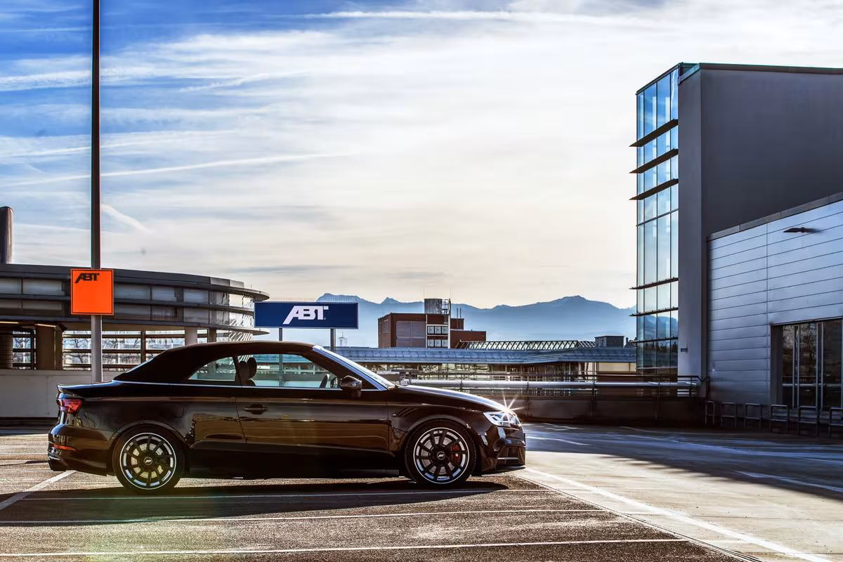 Audi: Schwarzer ABT Cabriolet vor Firmengebäude mit Bergpanorama im Hintergrund