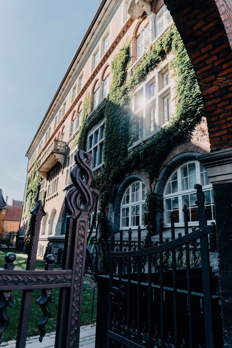 Copenhagen: Historisches Backsteingebäude mit Efeu und schmiedeeisernem Tor im Vordergrund.