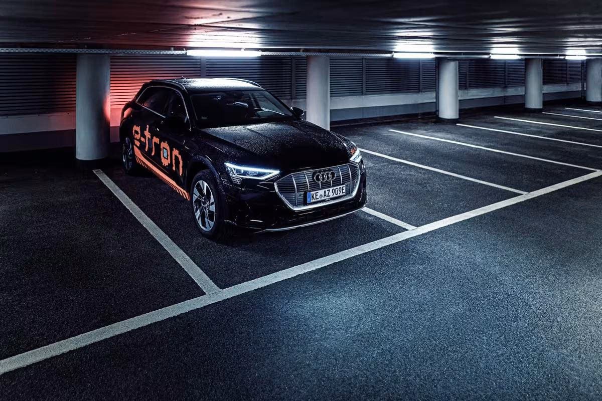 Black Audi e-tron with orange lettering parked in an underground garage.