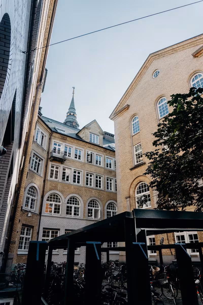 Copenhagen: Historische Backsteinfassaden und Kirchturm in Kopenhagen vor einem Fahrradständer.